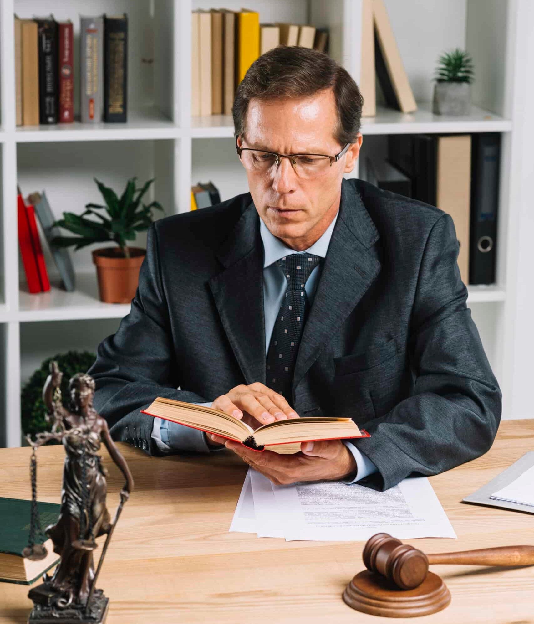mature male lawyer reading book with gavel justice statue wooden table scaled e1770782687345