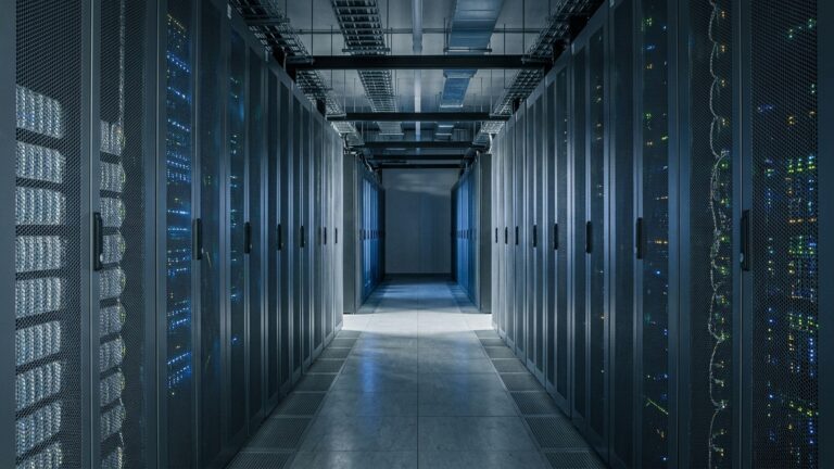A quiet server room corridor lit by the racks, seen down its length