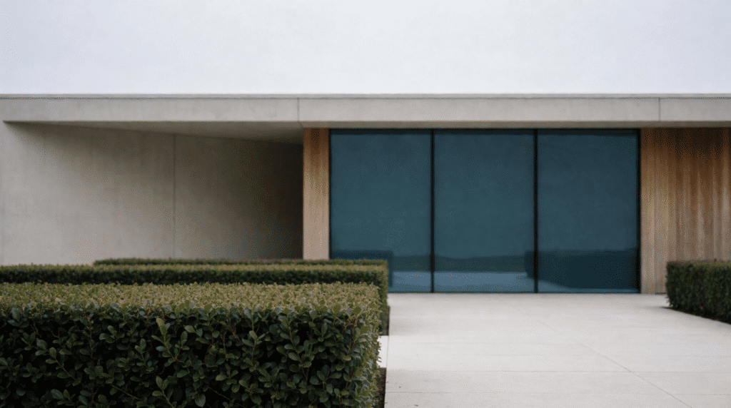 Modern concrete and glass court building with trimmed hedges under a grey sky