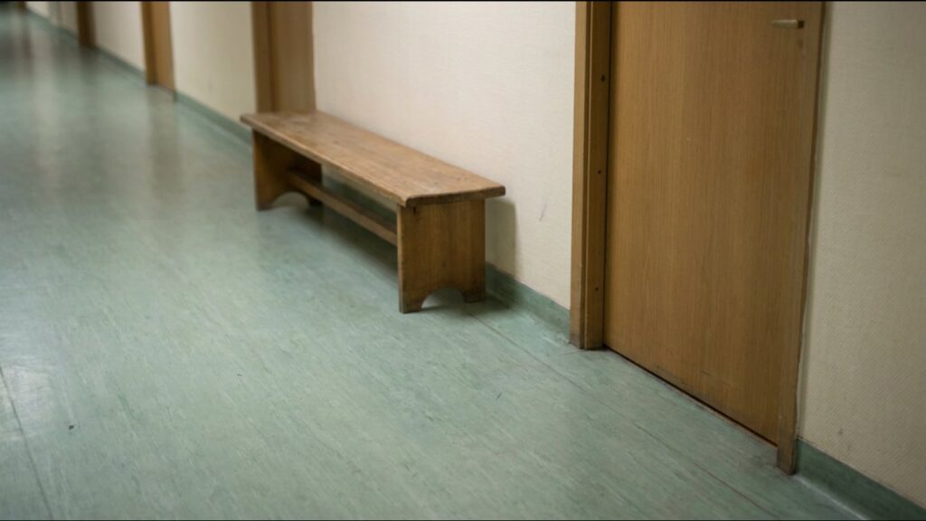 Empty wooden bench in a quiet hospital corridor
