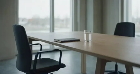 Empty meeting room with two office chairs on opposite sides of a long wooden table