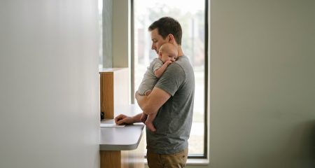 A father holding his baby at a municipal counter while registering the acknowledgement of his child