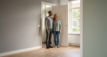 A couple standing in the doorway of an empty Dutch house holding the keys
