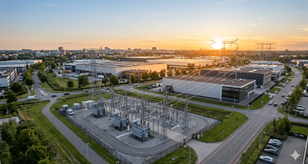 Closed distribution system with a transformer substation and high-voltage pylons on an industrial estate at sunset